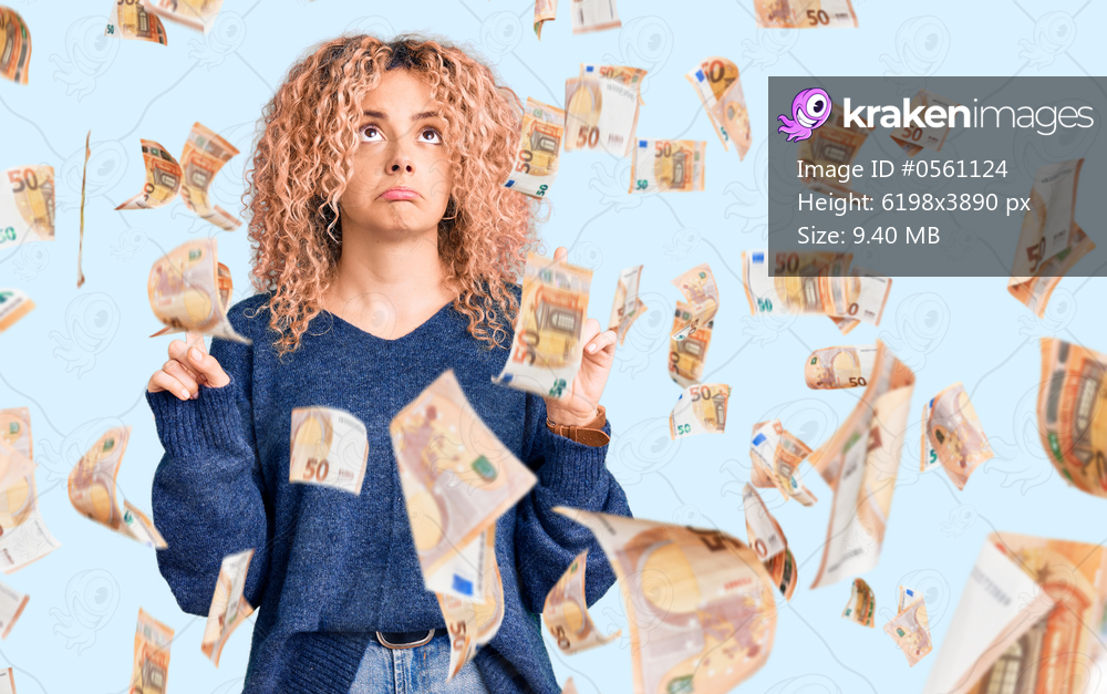 Young blonde woman with curly hair wearing casual winter sweater pointing up looking sad and upset, indicating direction with fingers, unhappy and depressed.