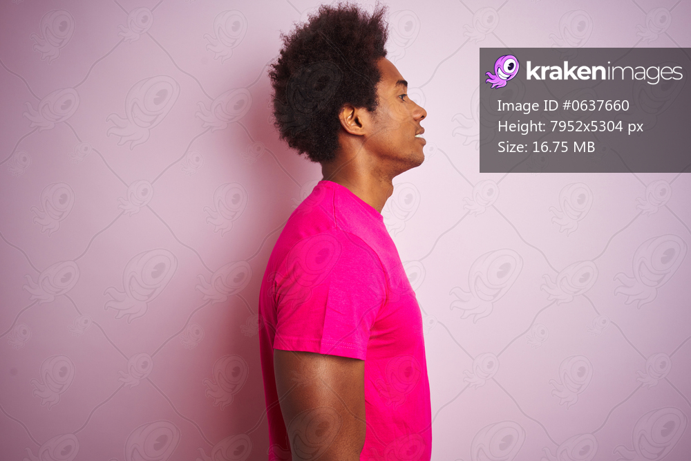 Young american man with afro hair wearing t-shirt standing over isolated pink background looking to side, relax profile pose with natural face with confident smile.