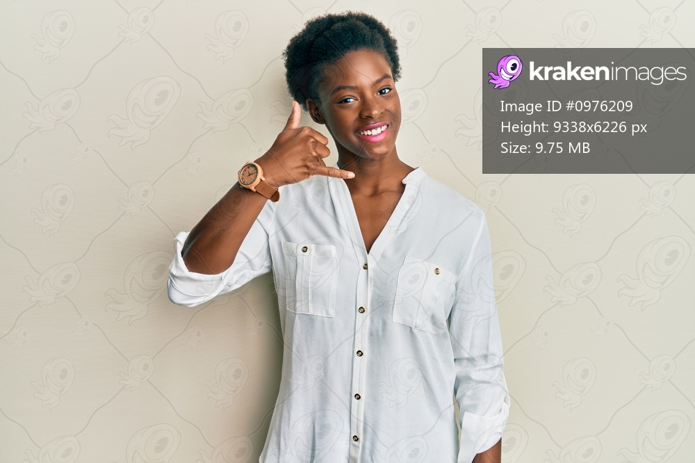 Young african american girl wearing casual clothes smiling doing phone gesture with hand and fingers like talking on the telephone. communicating concepts. 