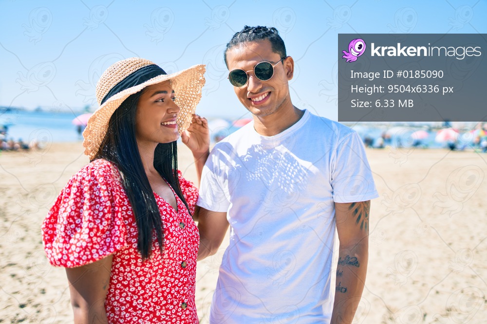 Young latin couple smiling happy and hugging at the beach.