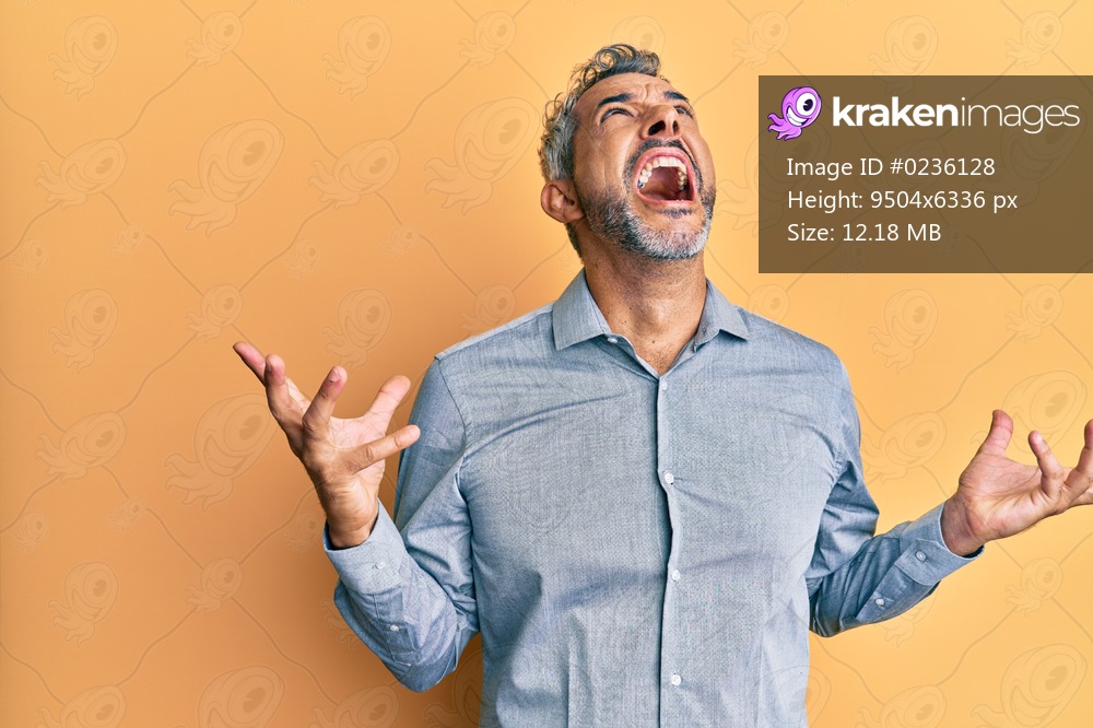 Middle age grey-haired man wearing casual clothes crazy and mad shouting and yelling with aggressive expression and arms raised. frustration concept. 