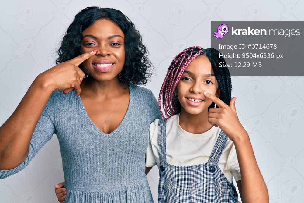 Beautiful african american mother and daughter wearing casual clothes and hugging pointing with hand finger to face and nose, smiling cheerful. beauty concept 