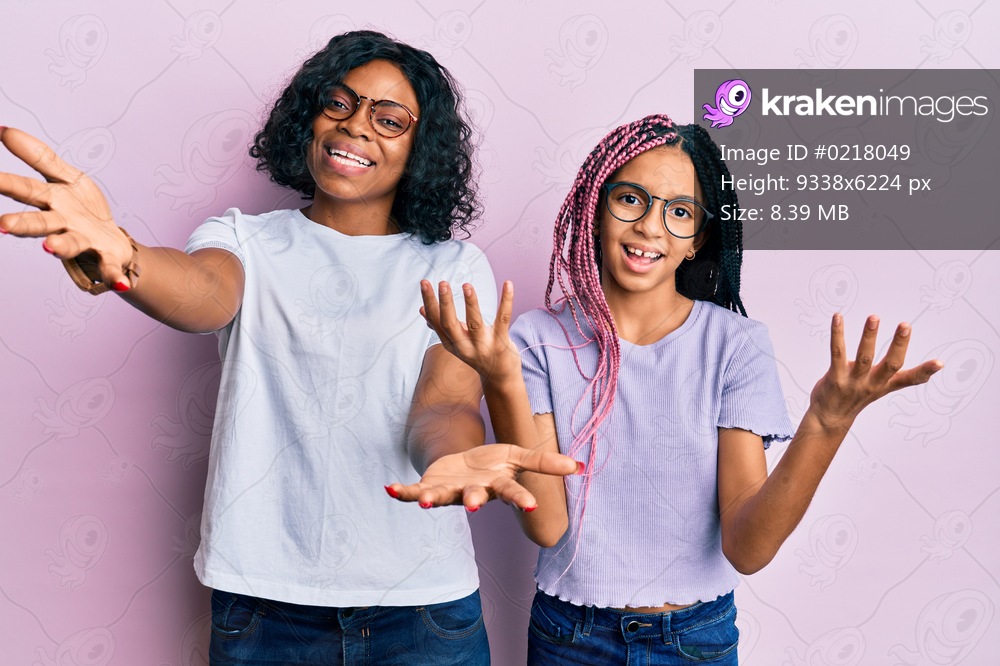 Beautiful african american mother and daughter wearing casual clothes and glasses smiling cheerful offering hands giving assistance and acceptance. 