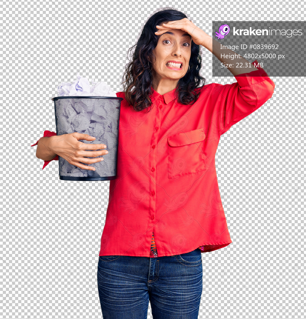 Young beautiful hispanic woman holding paper bin full of crumpled papers stressed and frustrated with hand on head, surprised and angry face