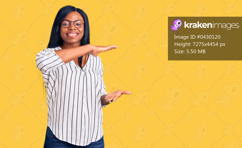 Young african american woman wearing casual clothes and glasses gesturing with hands showing big and large size sign, measure symbol. smiling looking at the camera. measuring concept. 