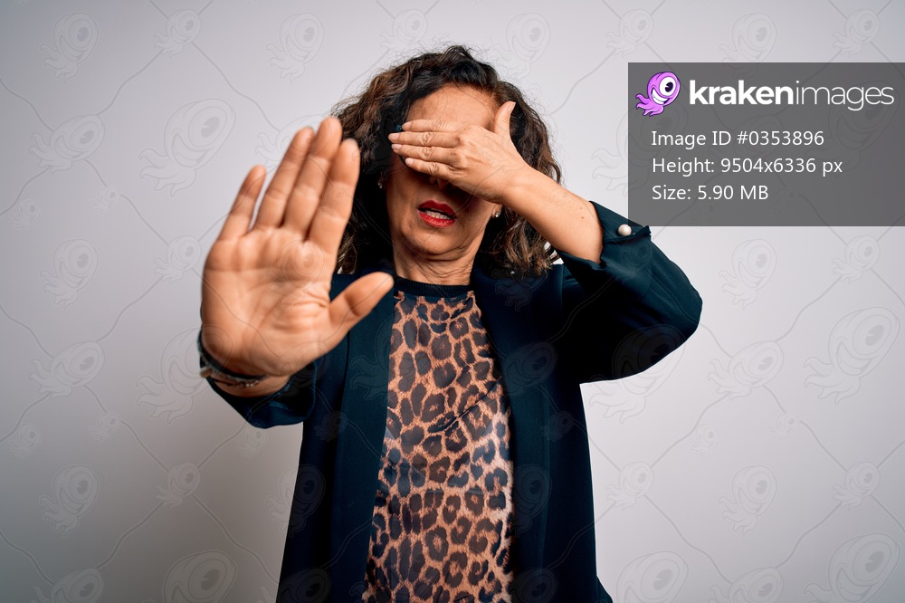 Middle age brunette business woman wearing glasses standing over isolated white background covering eyes with hands and doing stop gesture with sad and fear expression. Embarrassed and negative concept.