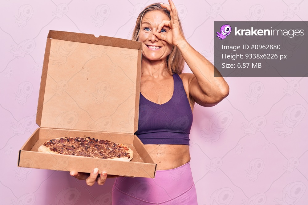 Middle age caucasian blonde woman wearing workout clothes and holding pizza box smiling happy doing ok sign with hand on eye looking through fingers 