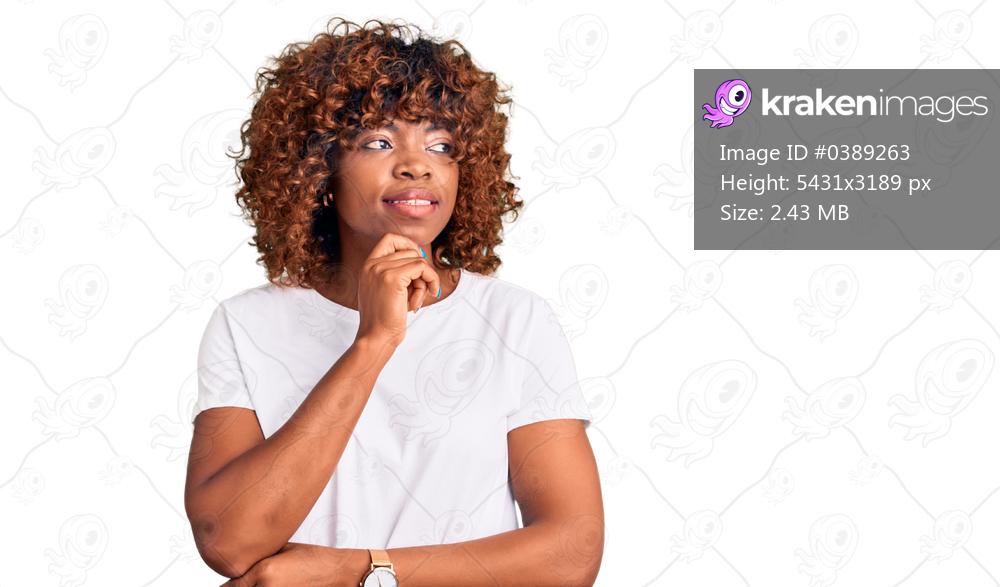 Young african american woman wearing casual white tshirt with hand on chin thinking about question, pensive expression. smiling with thoughtful face. doubt concept. 