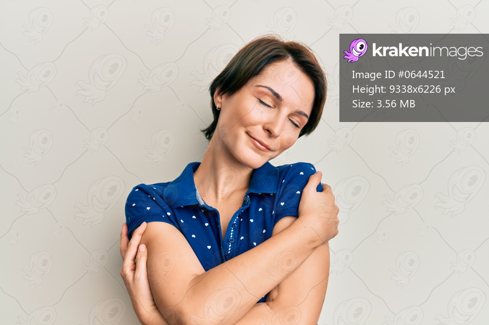 Young brunette woman with short hair wearing casual clothes hugging oneself happy and positive, smiling confident. self love and self care 