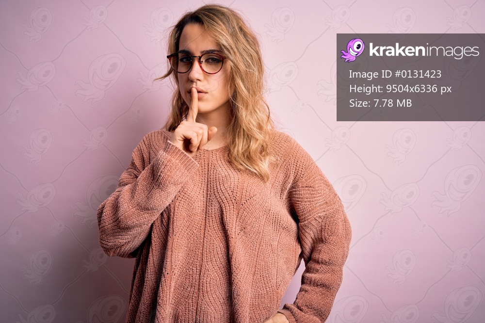 Young beautiful blonde woman wearing casual sweater and glasses over pink background asking to be quiet with finger on lips. Silence and secret concept.