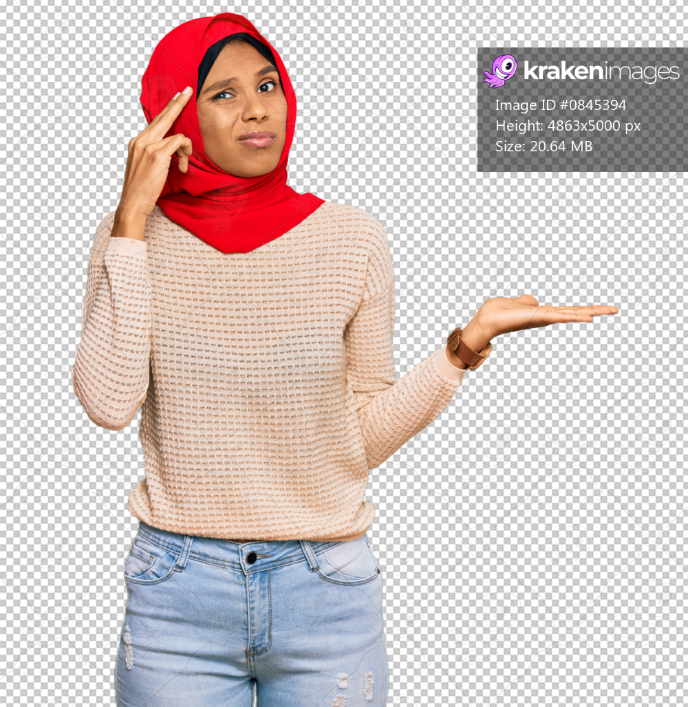 Young african american woman wearing traditional islamic hijab scarf confused and annoyed with open palm showing copy space and pointing finger to forehead. think about it.