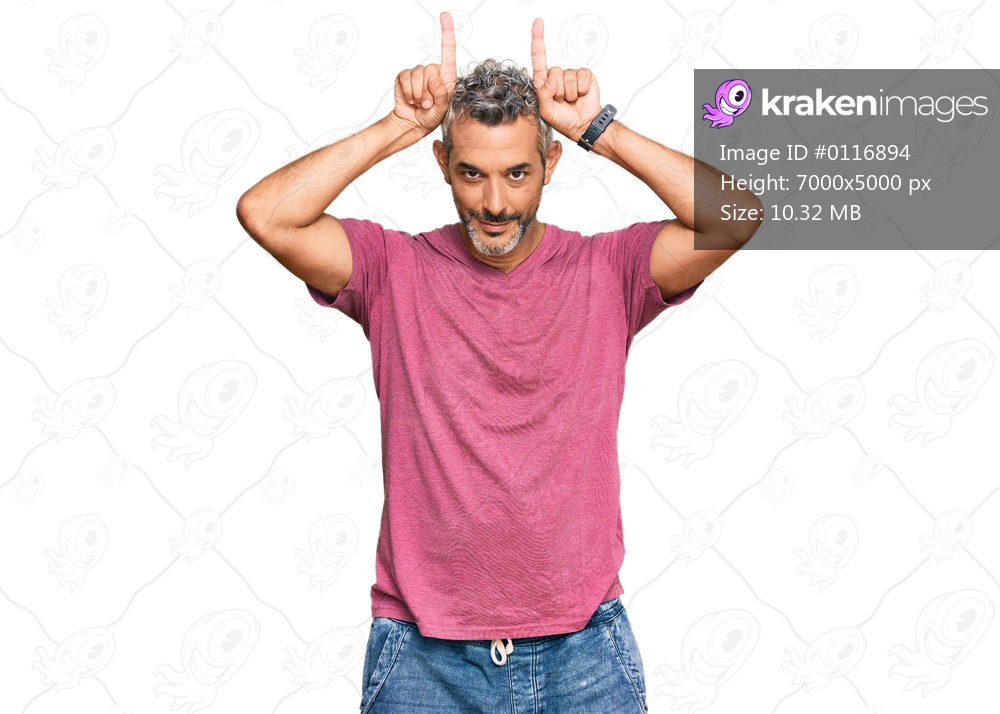 Middle age grey-haired man wearing casual clothes doing funny gesture with finger over head as bull horns 