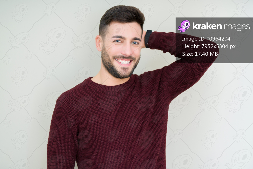 Young handsome man wearing a sweater over isolated background Smiling confident touching hair with hand up gesture, posing attractive