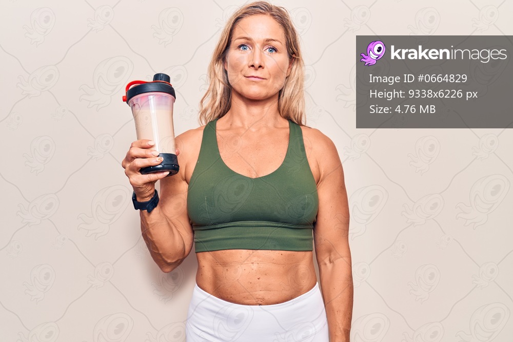 Middle age caucasian blonde woman wearing sport clothes drinking a protein shake thinking attitude and sober expression looking self confident 