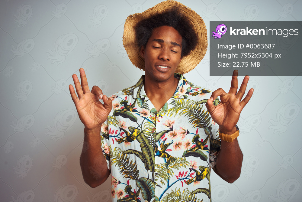 Afro american man on vacation wearing summer shirt and hat over isolated white background relax and smiling with eyes closed doing meditation gesture with fingers. Yoga concept.