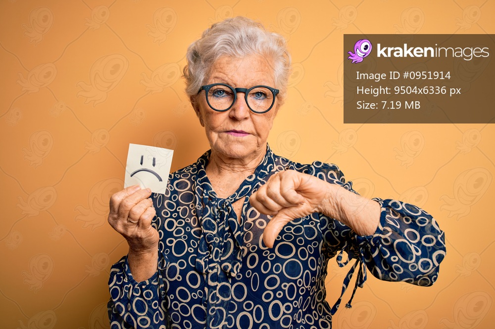 Senior beautiful grey-haired woman holding reminder paper with sad emotion face with angry face, negative sign showing dislike with thumbs down, rejection concept