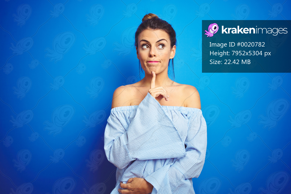 Young beautiful woman wearing bun hairstyle over blue isolated background Thinking concentrated about doubt with finger on chin and looking up wondering