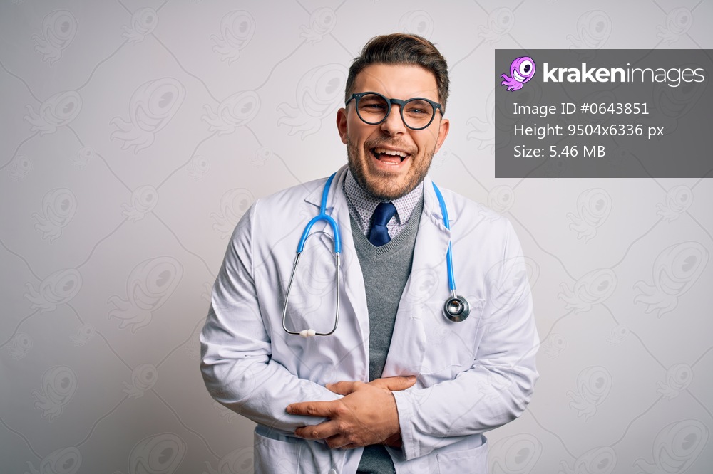 Young doctor man with blue eyes wearing medical coat and stethoscope over isolated background smiling and laughing hard out loud because funny crazy joke with hands on body.