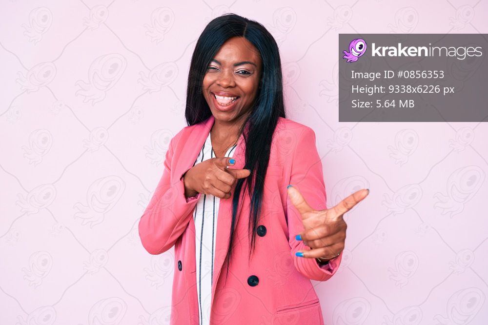 Young african american woman wearing business clothes pointing fingers to camera with happy and funny face. good energy and vibes. 