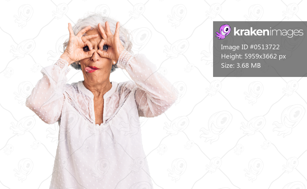 Senior grey-haired woman wearing casual clothes doing ok gesture like binoculars sticking tongue out, eyes looking through fingers. crazy expression. 