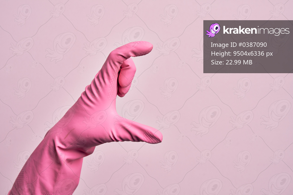 Hand of caucasian young man with cleaning glove over isolated pink background picking and taking invisible thing, holding object with fingers showing space