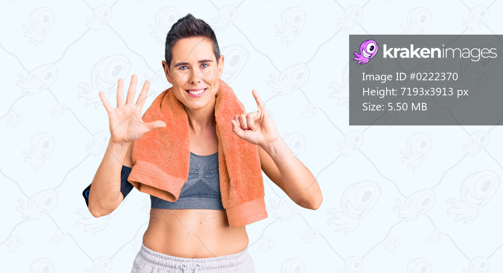 Young woman with short hair wearing sportswear and towel using smartphone showing and pointing up with fingers number six while smiling confident and happy. 