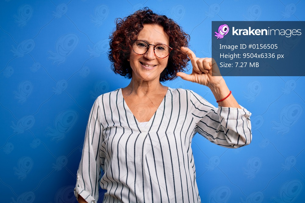 Middle age beautiful curly hair woman wearing casual striped shirt over isolated background smiling and confident gesturing with hand doing small size sign with fingers looking and the camera. Measure concept.