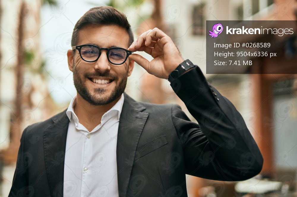 Young hispanic businessman smiling happy standing at the city.