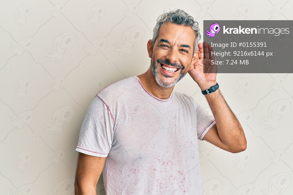 Middle age grey-haired man wearing casual clothes smiling with hand over ear listening an hearing to rumor or gossip. deafness concept. 