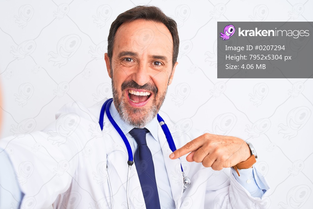 Middle age doctor man wearing stethoscope make selfie over isolated white background with surprise face pointing finger to himself