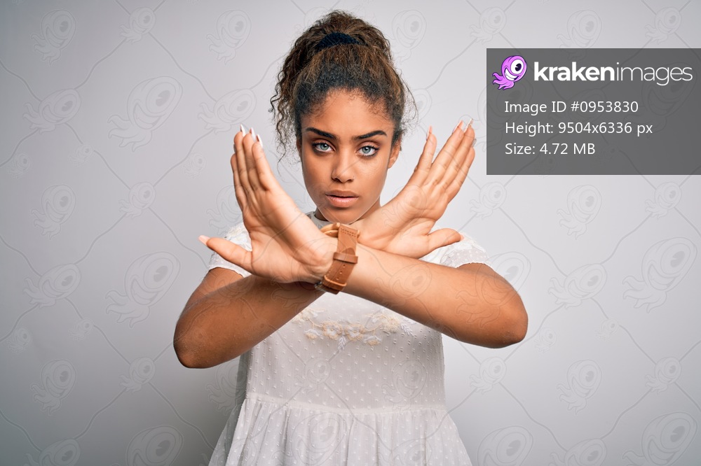 Young beautiful african american girl wearing casual t-shirt standing over white background Rejection expression crossing arms doing negative sign, angry face