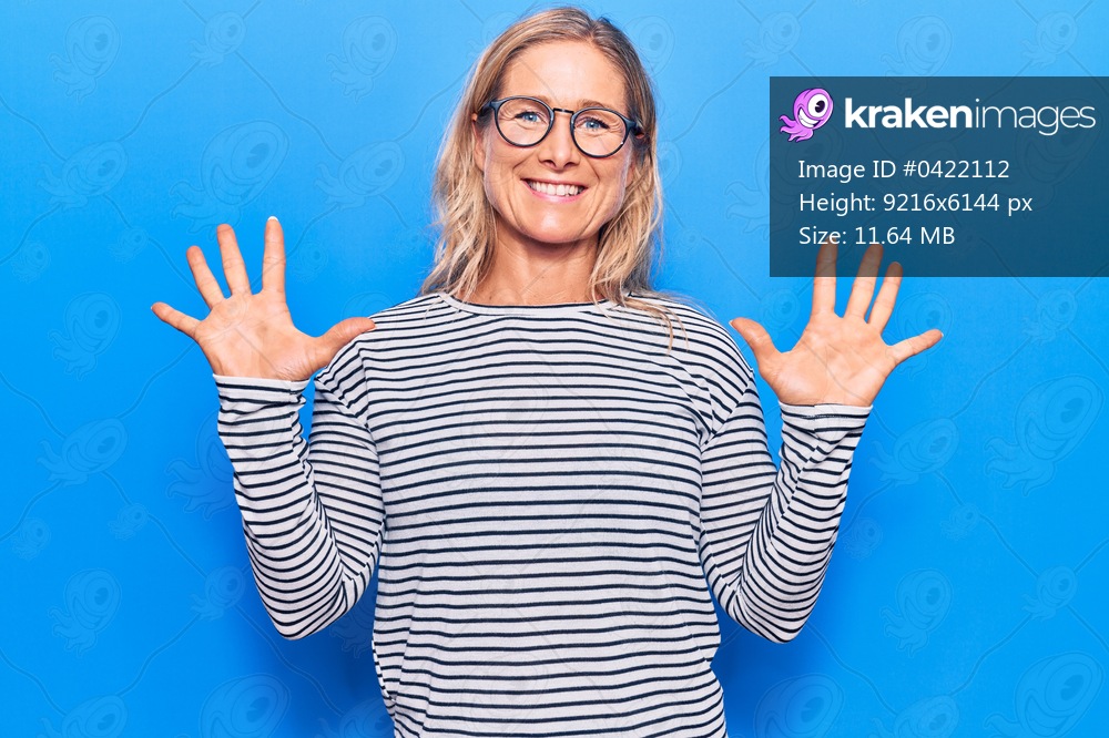 Middle age caucasian blonde woman wearing casual striped sweater and glasses showing and pointing up with fingers number ten while smiling confident and happy. 
