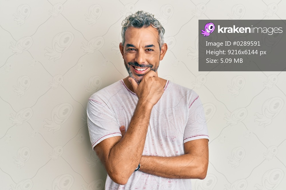 Middle age grey-haired man wearing casual clothes looking confident at the camera smiling with crossed arms and hand raised on chin. thinking positive. 