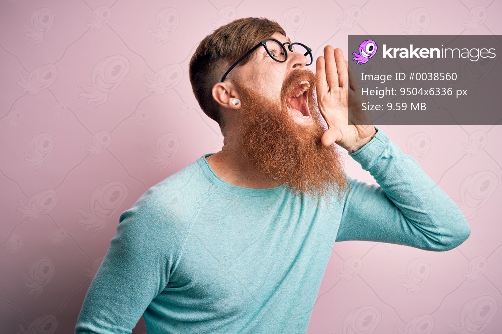 Handsome Irish redhead man with beard wearing glasses over pink isolated background shouting and screaming loud to side with hand on mouth. Communication concept.