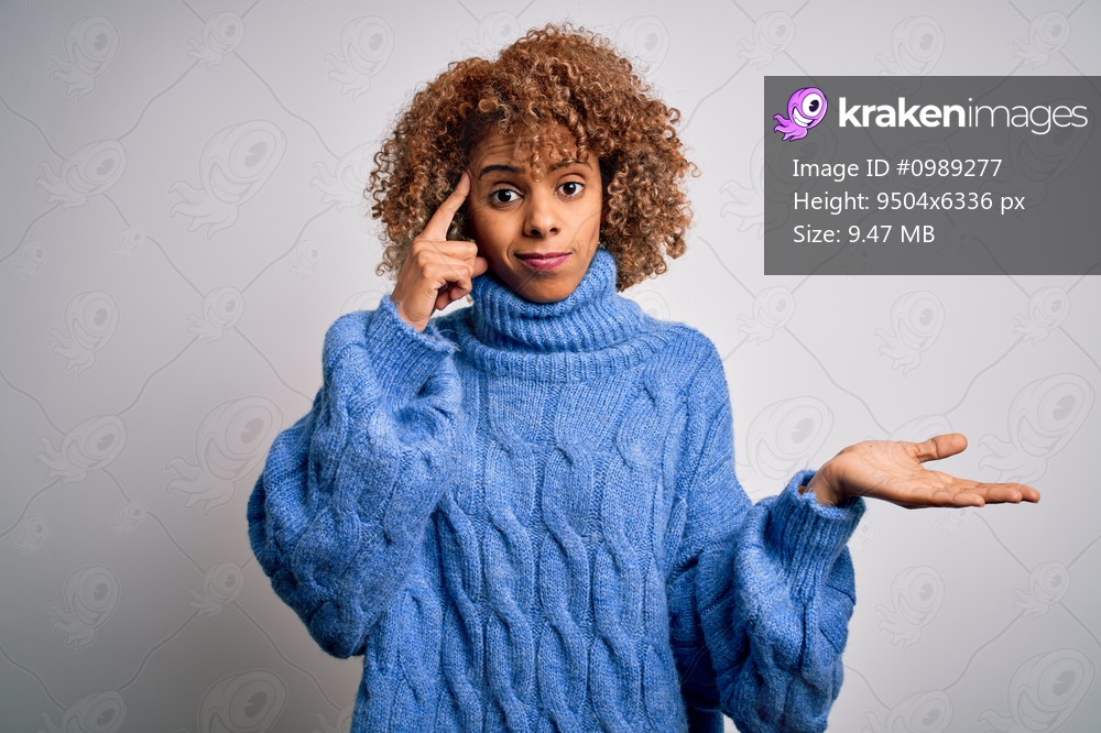 Young beautiful african american woman wearing turtleneck sweater over white background confused and annoyed with open palm showing copy space and pointing finger to forehead. Think about it.