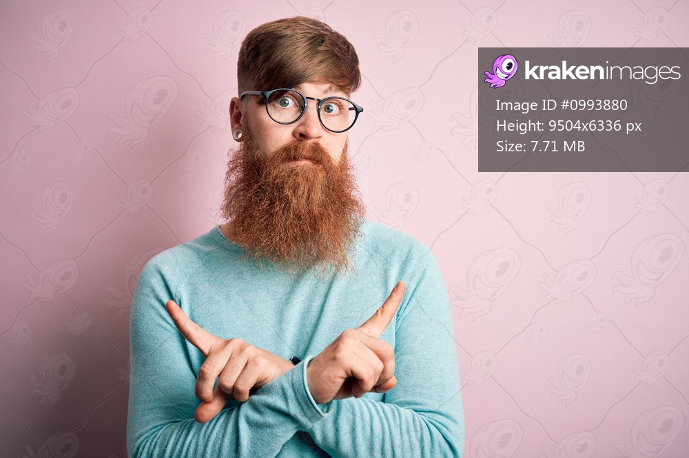 Handsome Irish redhead man with beard wearing glasses over pink isolated background Pointing to both sides with fingers, different direction disagree