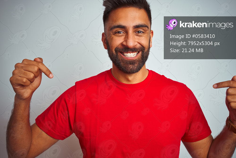 Young indian man wearing red t-shirt over isolated white background looking confident with smile on face, pointing oneself with fingers proud and happy.