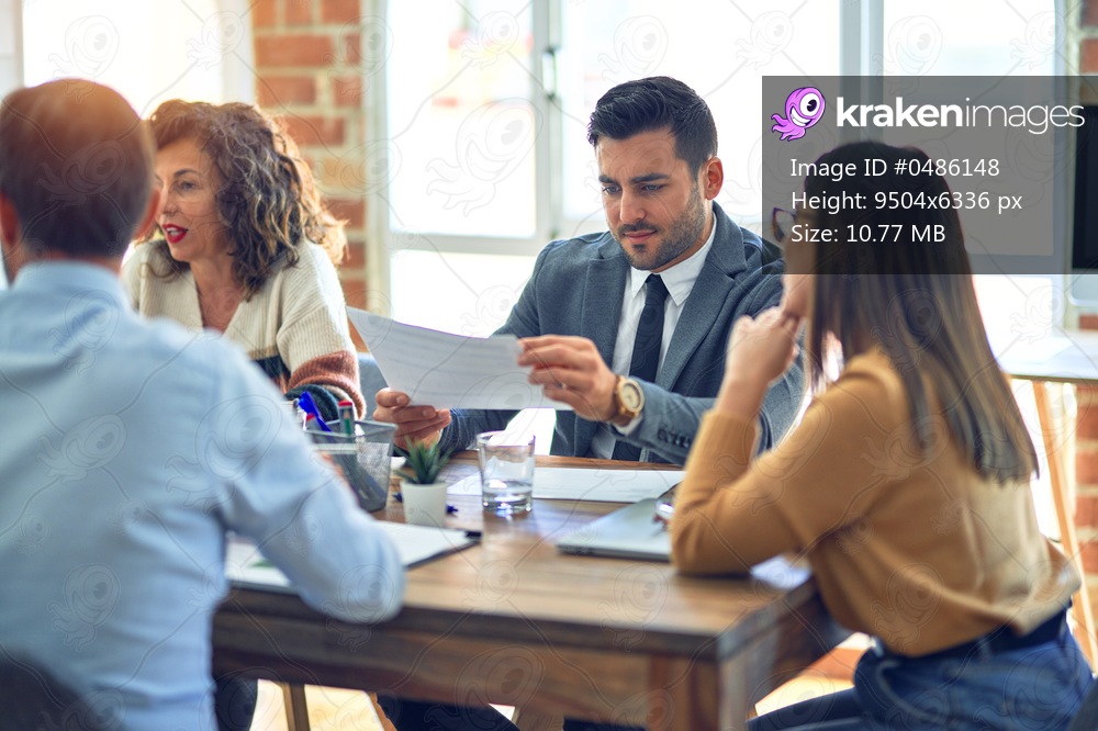 Group of business workers working together. Sitting on desk reading documents at the office