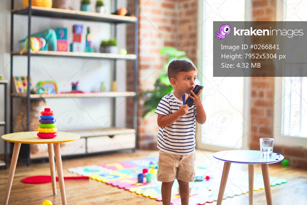 Beautiful toddler boy talking on the smartphone at kindergarten