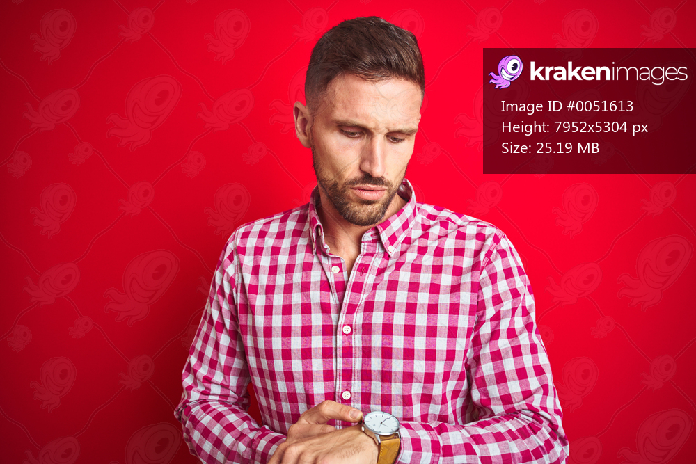 Young handsome man over red isolated background Checking the time on wrist watch, relaxed and confident