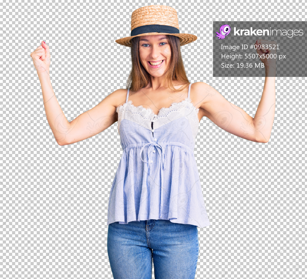 Beautiful brunette young woman wearing summer hat screaming proud, celebrating victory and success very excited with raised arms