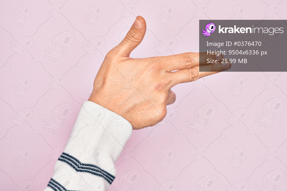 Hand of caucasian young man showing fingers over isolated pink background gesturing fire gun weapon with fingers, aiming shoot symbol