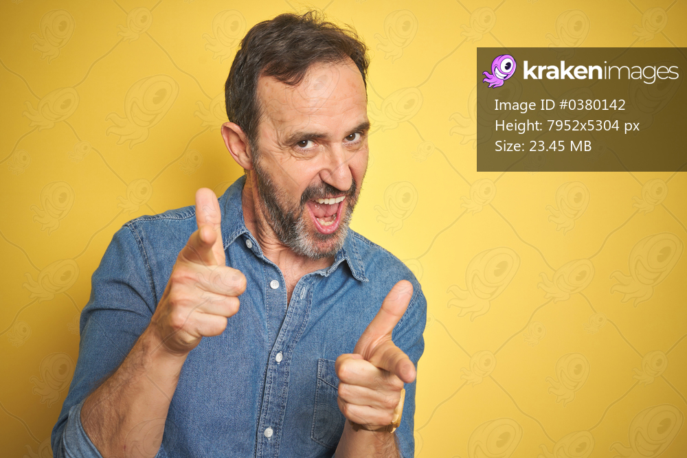 Handsome middle age senior man with grey hair over isolated yellow background pointing fingers to camera with happy and funny face. Good energy and vibes.