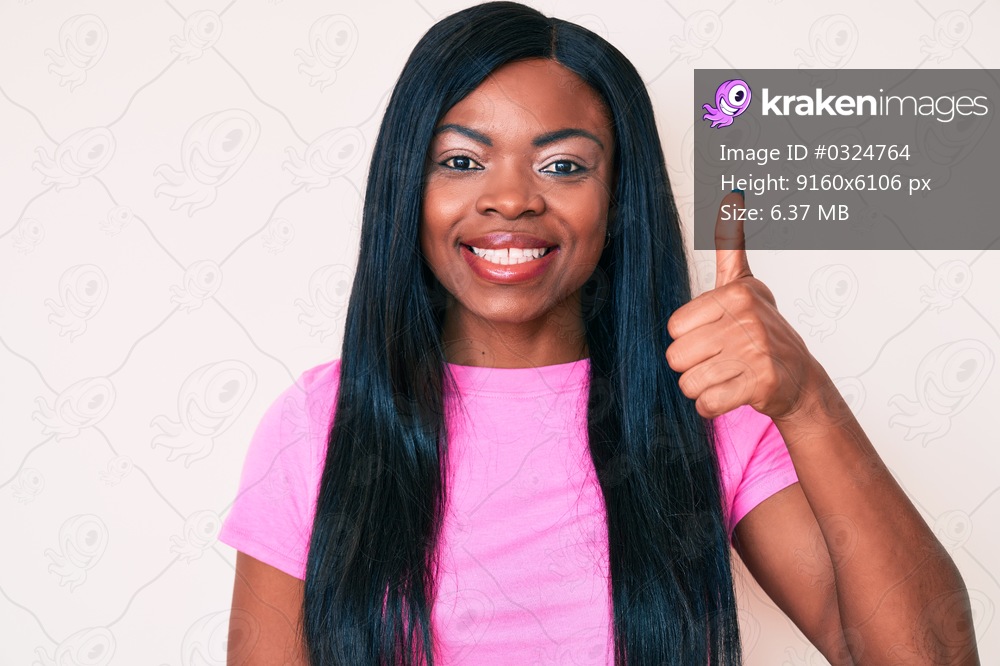Young african american woman wearing casual clothes smiling happy and positive, thumb up doing excellent and approval sign 
