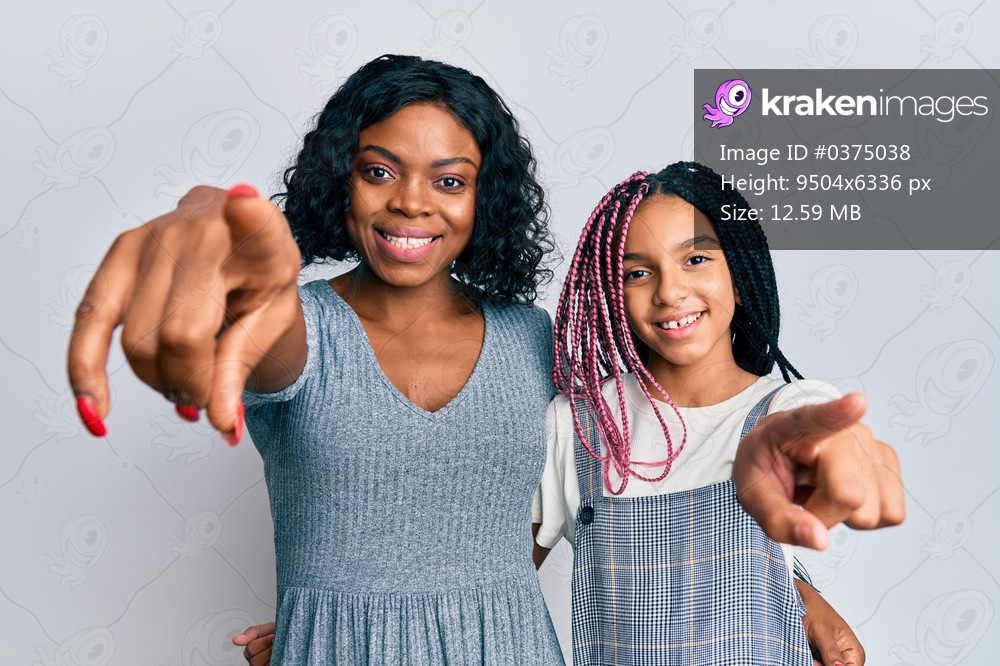 Beautiful african american mother and daughter wearing casual clothes and hugging pointing to you and the camera with fingers, smiling positive and cheerful 