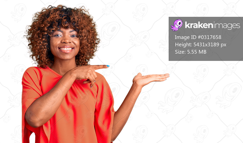 Young african american woman wearing casual clothes amazed and smiling to the camera while presenting with hand and pointing with finger. 