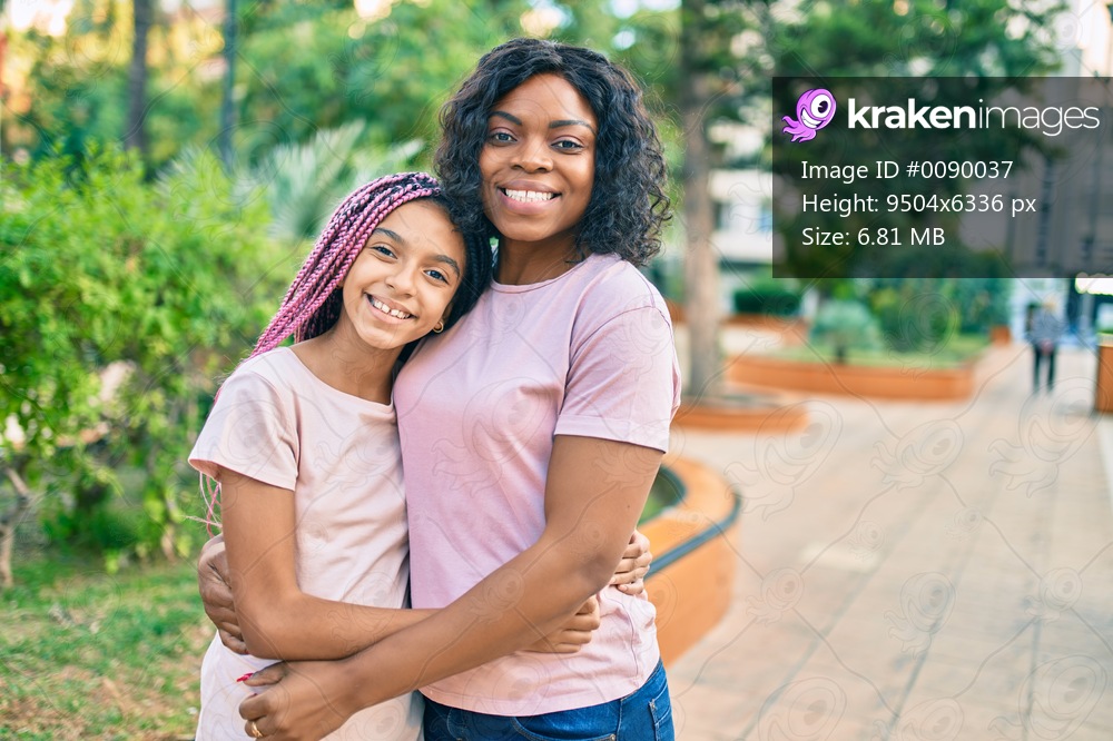 Beautiful african american mother and daughter smiling happy and hugging. Standing with smile on face standing at the park.
