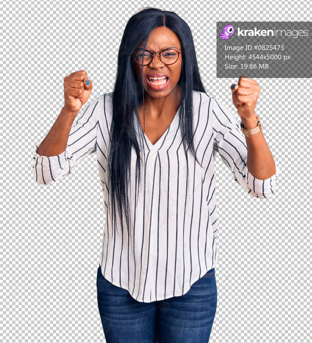Young african american woman wearing casual clothes and glasses angry and mad raising fists frustrated and furious while shouting with anger. rage and aggressive concept.