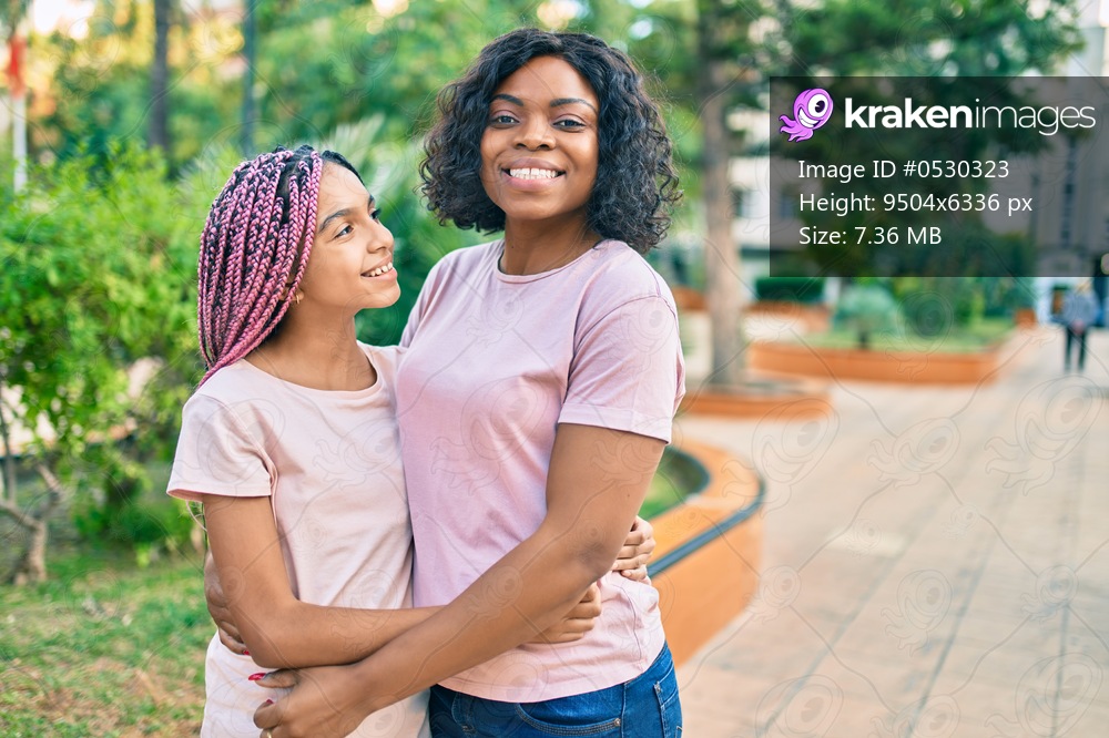 Beautiful african american mother and daughter smiling happy and hugging. Standing with smile on face standing at the park.