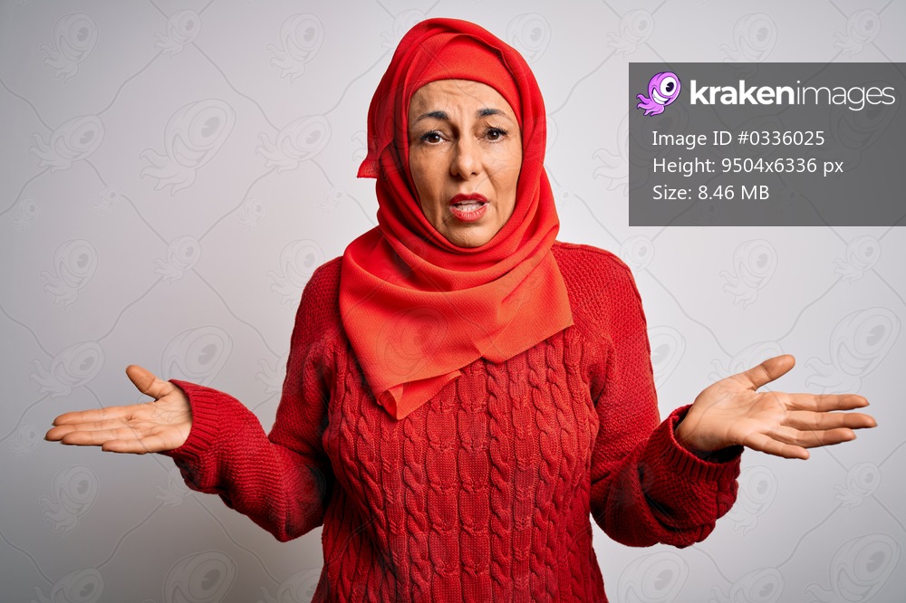 Middle age brunette woman wearing muslim traditional hijab over isolated white background clueless and confused with open arms, no idea concept.